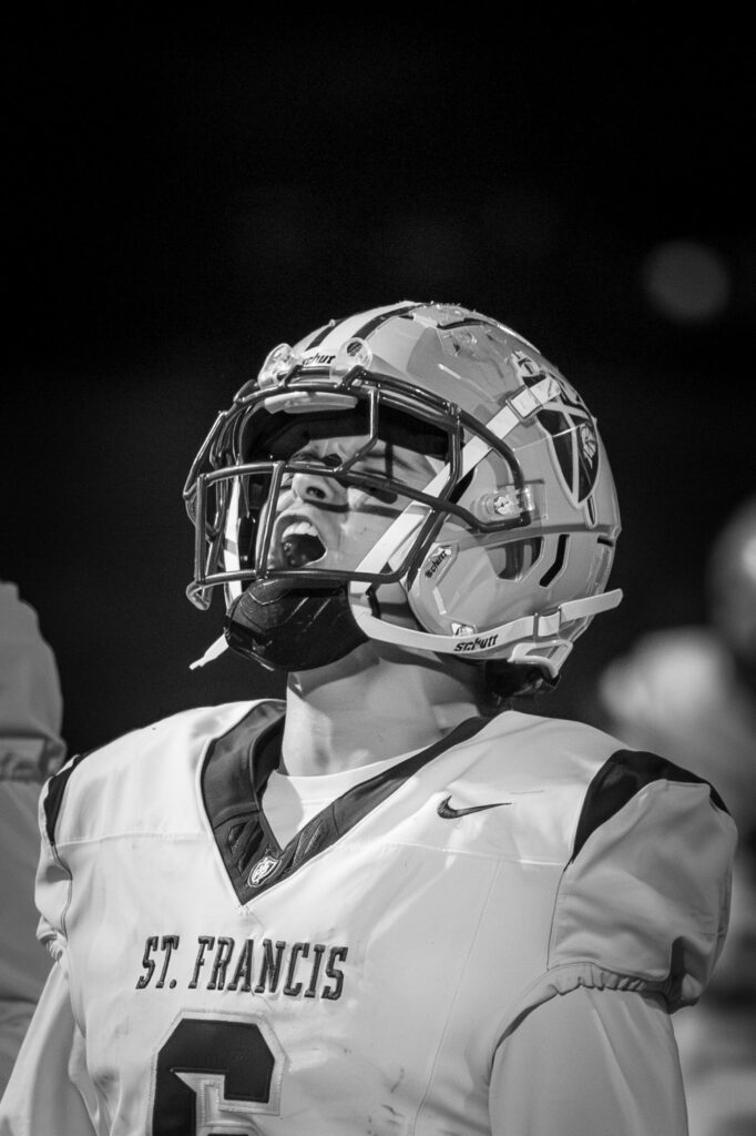 Football player in St. Francis jersey number 6 wearing helmet shouting during a game.
